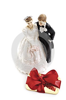 Gold bar with a red ribbon, bride and groom figurines in background