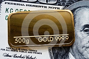 Gold bar weighing 500 grams 999.9, fineness against a blurred background of dollar
