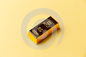 A gold bar on a yellow background. Financial concept. Flat lay. Top view. The concept of a gold reserve. A protective financial as