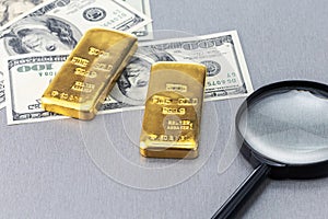 Gold bars, US dollar banknotes money and magnifying glass.