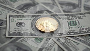 Gold Bitcoin BTC coins rotating on bills of 100 dollars. Worldwide virtual internet cryptocurrency and digital payment