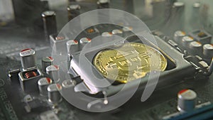 A gold Bitcoin coin with glare and reflection installed instead of a central processor in the motherboard with electronic