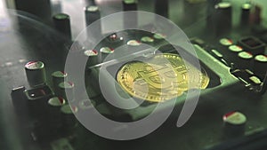 A gold Bitcoin coin with glare and reflection installed instead of a central processor in the motherboard with electronic