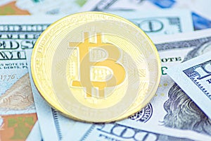 Gold Bitcoin on hundred dollars bills. Golden symbolic coin Bitcoin on banknotes of one hundred dollars. Cryptocurrency