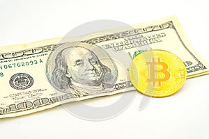 Gold Bitcoin on hundred dollars bills. Golden symbolic coin Bitcoin on banknotes of one hundred dollars. Cryptocurrency