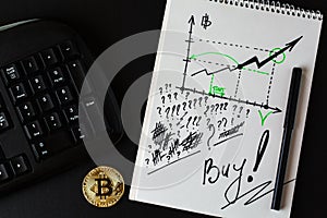 Gold bitcoin, part of keyboard and ring-bound notebook with diagram with increasing of digital currency of bitcoin