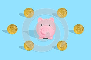 . Gold bitcoins with a pink piggy bank on a blue background. The concept of profitable investment of savings