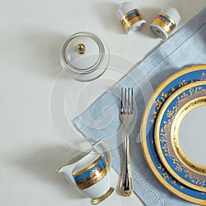 Gold blue tableware, dishes, plates, utensils on the table