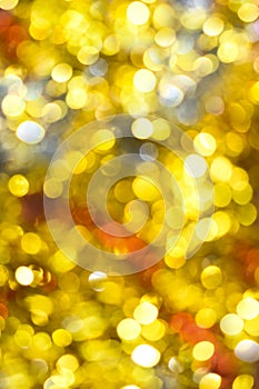 Gold bokeh background. Texture with shining blurred lights in yellow, red and silver. Abstract Christmas festive background.