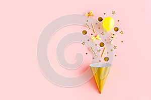 Gold box with confetti, balloons, streamers and decoration on a pink background. Colorful celebration, birthday