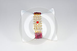 gold bracelet with diamond polki and red stone in middle with pillow on white background