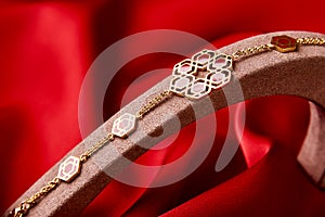 Gold bracelet on a red background with copy space