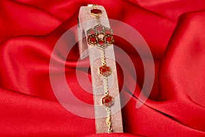 Gold bracelet on a red background with copy space