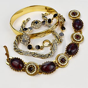 Gold bracelet with red and black stones on a white background close up