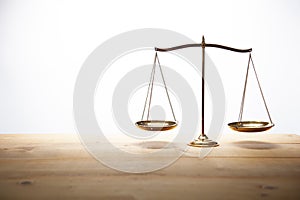 Gold brass balance scale on wooden desk and white backdrop