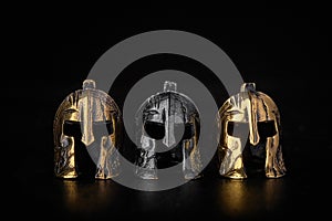 Gold, bronze and metal Spartan helmet on a black background