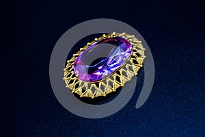 Gold brooch jewelry in the center of which is a purple stone