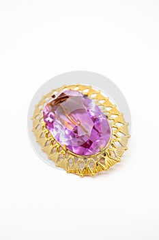 Gold brooch jewelry in the center of which is a purple stone