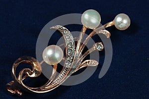 Gold brooch with pearls on dark blue background