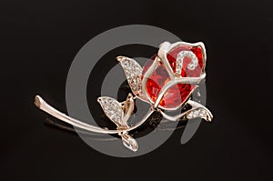 Gold brooch rose flower with red stone isolated on black