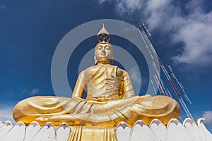 Gold Buddha Image with blue sky and scattering cloud.