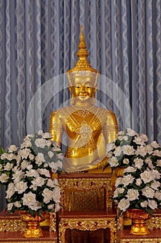 Gold Buddha statue and flowers in the shire