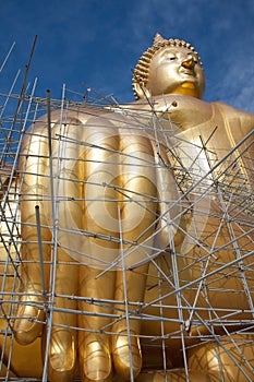 Gold buddha statue under construction in Thai temple with clear sky.WAT MUANG, Ang Thong, THAILAND.