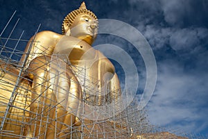 Gold buddha statue under construction in Thai temple with clear sky.WAT MUANG, Ang Thong, THAILAND.