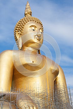 Gold buddha statue under construction in Thai temple with clear sky.WAT MUANG, Ang Thong, THAILAND.