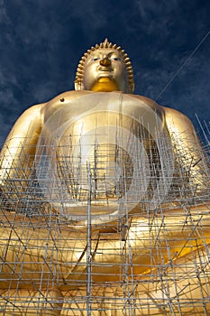 Gold buddha statue under construction in Thai temple with clear sky.WAT MUANG, Ang Thong, THAILAND.