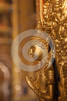 Gold buddha statue on the wall in church at buddhist temple in T