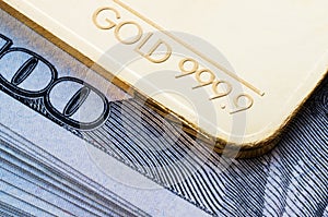 Gold bullion 999.9 fineness against the background of a hundred-dollar bills