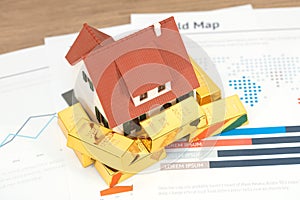 Gold bullion and house model on documents