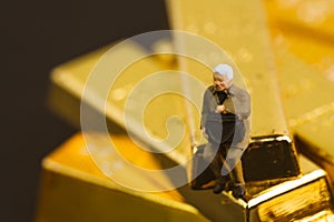 Gold, bullion or ingot in wealth management or investment asset allocation concept, miniature people manager businessman with