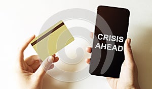 Gold card and phone with text disaster recover plan CRISIS AHEAD in the female hands