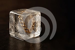 A gold chain inside an ice cube. Space for text.