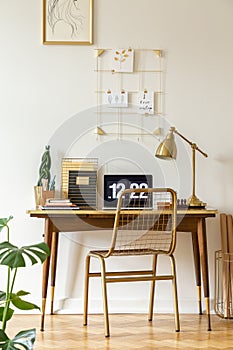 Gold chair at desk with laptop and lamp in classic freelancer`s interior. Real photo