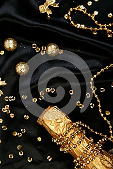 Gold Champagne bottle with confetti stars and party streamers on festive black background. Christmas, birthday or wedding concept.
