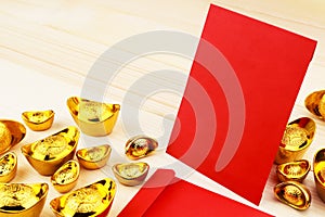 Gold Chinese ingot Yuan Bao and Blank red envelopes on wooden background