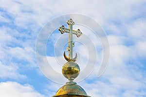 Gold Christian cross on a background of blue sky.