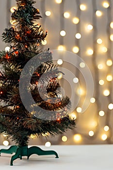 Gold Christmas background of de-ocused lights garland with decorated tree