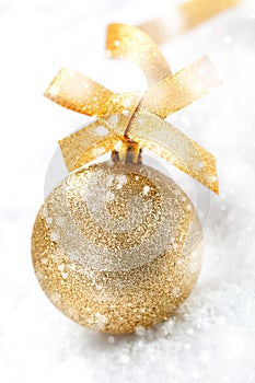 Gold Christmas ball in falling snow