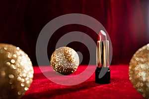 Gold christmas balls and red lipstick on red background