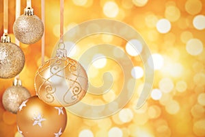 Gold Christmas baubles hanging in front of a gold background