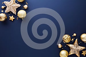 Gold Christmas decorations on dark blue background. Frame of sparkle Xmas stars and baubles. Flat lay, top view