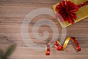 Gold Christmas gift boxes with red bouquet. Spruce branch and red unwinded Christmas gift wrapping tape on a wooden table. Top