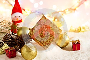 Gold Christmas gift boxes with snowman and bauble on snow in lighting colorful