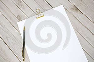 Gold clip and white paper on wooden background