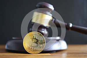 Gold coin bitcoin lying next to judge hammer closeup