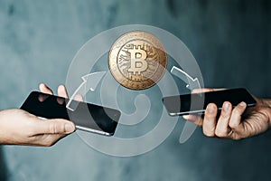 Gold coin Bitcoin payment from phone to phone, hands and TVs close-up. The concept of crypto currency. blockchain technology. photo